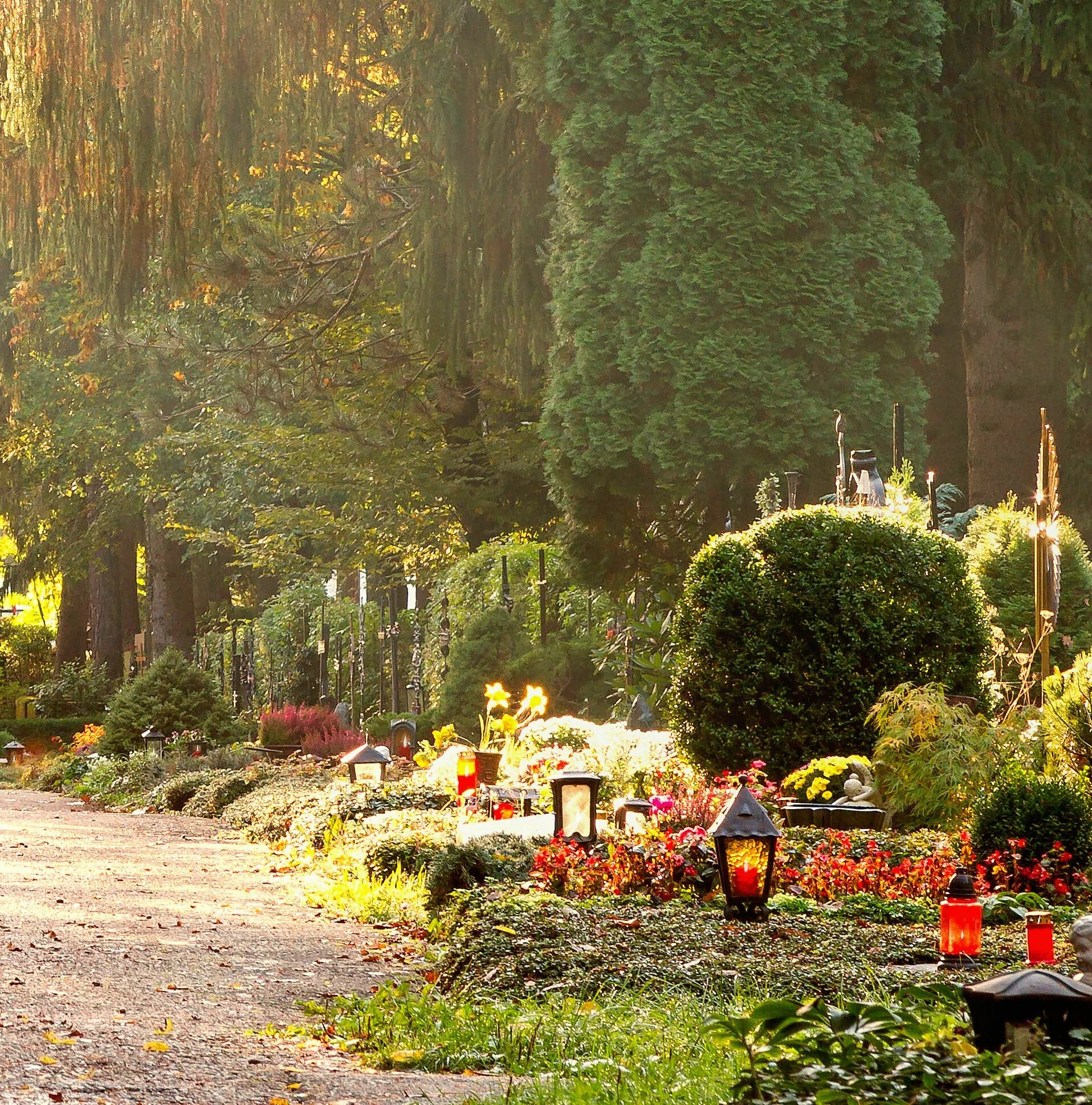 Weg, der über den Friedhof führt mit schön geschmückten Gräbern bei Herbst
